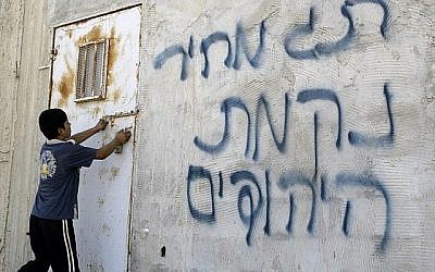 Un Palestinien ouvre une porte après que des graffitis en hébreu ont été tagués sur un mur, apparemment par des résidents d'implantations juifs, dans le village d'Aqraba, en Cisjordanie, près de la ville de Naplouse, le 2 juillet 2014 (AFP / JAAFAR ASHTIYEH)