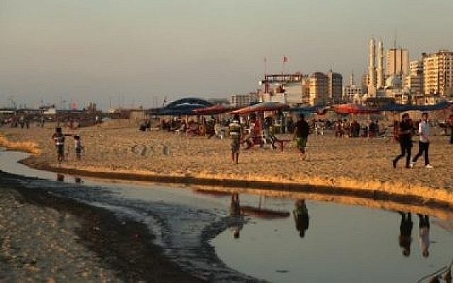 Des Palestiniens sur une plage, à côté des eaux polluées, à Gaza, le 3 juillet 2017 (Crédit : AFP Photo/Mahmud Hams)