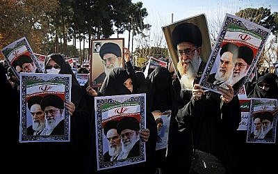 Des manifestants pro-gouvernementaux brandissent des affiches du leader suprême iranien, l'ayatollah Ali Khamenei et du fondateur iranien de la République islamique, l'ayatollah Ruhollah Khomeiny, lors d'une marche dans la ville sainte iranienne de Qom le 3 janvier 2018 (Crédit : AFP PHOTO / Mohammad ALI MARIZAD)