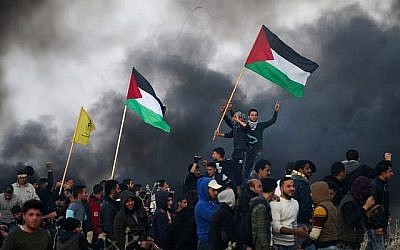 Des manifestants palestiniens agitent des drapeaux nationaux lors d'affrontements avec les forces de sécurité israéliennes dans la banlieue est de la ville de Gaza, près de la frontière avec Israël, le 12 janvier 2018. (AFP PHOTO / MOHAMMED ABED)
