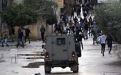 Des jeunes palestiniens jettent des pierres sur les forces israéliennes durant une opération militaire dans la ville de Jénine, en Cisjordanie, le 18 janvier 2018. (Crédit : AFP/Jaafar Ashtiyeh)