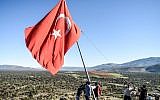 Des villageois réparent un drapeau turc, dans le village de Sugedik dans la province de, près de la frontière syrienne, le 20 janvier 2018.  (Crédit :AFP PHOTO / BULENT KILIC)