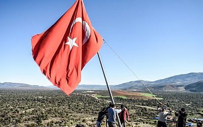Des villageois réparent un drapeau turc, dans le village de Sugedik dans la province de, près de la frontière syrienne, le 20 janvier 2018.  (Crédit :AFP PHOTO / BULENT KILIC)