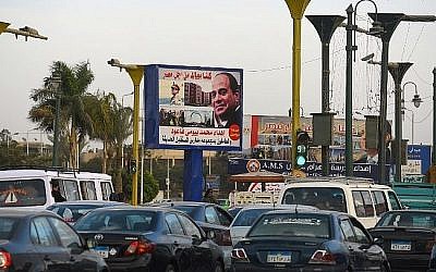Les Égyptiens passent devant un panneau d'affichage arborant l'image du président égyptien Abdel-Fattah el-Sissi, dans le cadre de la campagne pour sa réélection aux prochains scrutins prévus pour le mois de mars 2018, le 22 janvier 2018, au Caire (Crédit : PHOTO AFP / MOHAMED EL-SHAHED)