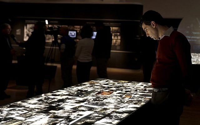 Un homme regarde les photos de l’exposition "Flash mémoriel" offre trois perspectives divergentes sur l'Holocauste: celle des nazis, des victimes juives et des soldats des forces alliées, à Yad Vashem, à Jérusalem, le 24 janvier 2018. (Crédit : GALI TIBBON / AFP)