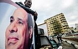 Un sympathisant du président égyptien Abdel Fattah el-Sissi se tient à l'arrière d'une camionnette arborant son portrait et ses haut-parleurs, sur la place Tahrir de la capitale, le 25 janvier 2018, alors que le pays marque le septième anniversaire du soulèvement de 2011 qui a mis fin au règne de 30 ans de l'ancien président Hosni Mubarak. (Crédit : AFP / MOHAMED EL-SHAHED)