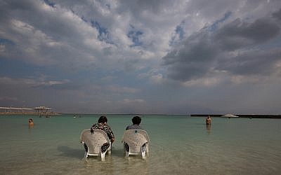 Des gens assis près de l'eau sur la plage de Hamei Zohar sur les rives de la mer Morte, le 10 novembre 2015 (Nati Shohat / Flash90)