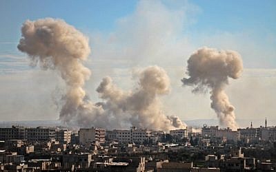 La fumée s'élève des bâtiments après le bombardement du village de Mesraba, dans la région assiégée de Ghouta Est, dans la banlieue de la capitale Damas, le 19 février 2018. (AFP PHOTO / Hamza Al-Ajweh)
