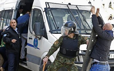 La police palestinienne empêche des manifestants d'approcher un véhicule transportant des membres du conseil municipal de New York et des groupes de la société civile alors qu'ils quittent un immeuble après avoir visité une ONG dans la ville de Ramallah, en Cisjordanie, le 22 février 2018 (Crédit : Abbas Momani/AFP)