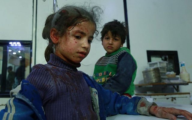 Deux enfants blessés attendent une aide médicale dans la ville de Douma, dans la région assiégée de la Ghouta aux abords de la capitale de Damas, suite aux frappes aériennes menées par les forces du régime, le 23 février 2018 (Crédit : AFP PHOTO / HAMZA AL-AJWEH) Deux enfants blessés attendent une aide médicale dans la ville de Douma, dans la région assiégée de la Ghouta aux abords de la capitale de Damas, suite aux frappes aériennes menées par les forces du régime, le 23 février 2018 (Crédit : AFP PHOTO / HAMZA AL-AJWEH)