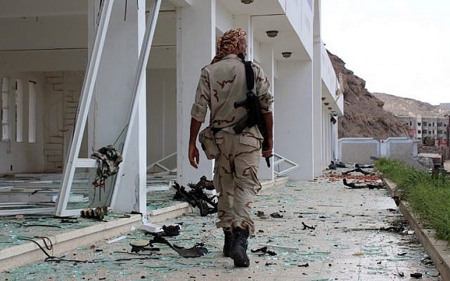 Un combattant du conseil de transition du sud séparatiste marche sur le site de deux attentats-suicides à la voiture piégée qui ont ciblé le siège d'une unité terroriste le jour précédent, dans le port d'Aden, dans le sud du Yémen, le 25 février 2018 (Crédit : AFP PHOTO / SALEH AL-OBEIDI)
