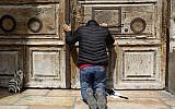 Un pèlerin prie devant la porte fermée de l'église du Saint-Sépulcre dans la Vieille Ville de Jérusalem, le 25 févcrier 2018 (Crédit :AFP PHOTO / GALI TIBBON)