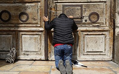 Un pèlerin prie devant la porte fermée de l'église du Saint-Sépulcre dans la Vieille Ville de Jérusalem, le 25 févcrier 2018 (Crédit :AFP PHOTO / GALI TIBBON)