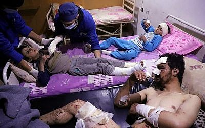 Les médecins soignent Omar, âgé de dix ans, qui a été blessé lors d'une frappe aérienne qui a tué plusieurs membres de sa famille dans leur maison d'Otaybah, dans l'enclave syrienne de Ghouta Est tenue par les rebelles, alors que son père et sa sœur de sept ans, Manar, le surveillent dans un hôpital de fortune le 25 février 2018. (AFP PHOTO / AMER ALMOHIBANY)