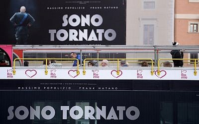Un bus de tourisme passe devant une affiche du film italien  "Sono Tornato" (Je suis de retour) dans le centre de Rome, le 2 février 2018 (AFP PHOTO / FILIPPO MONTEFORTE