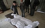Des enfants devant des cadavres emballés, après des frappes du régime dans la Ghouta orientale, en périphérie de Damas, le 5 février  2018. (Crédit : AFP / ABDULMONAM EASSA)