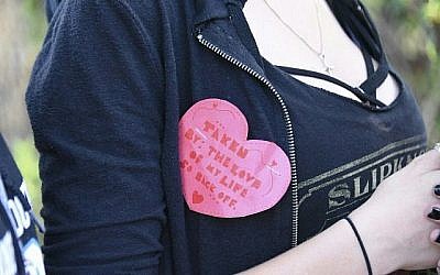 Une étudiante porte une épingle de la Saint-Valentin alors qu'elle sort du lycée Marjory Stoneman Douglas à Parkland, en Floride, une ville située à environ 80 kilomètres au nord de Miami le 14 février 2018 après une fusillade dans son lycée (Crédit : PHOTO AFP / Michele Eve Sandberg