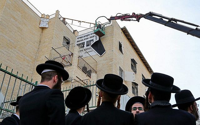 Les employés municipaux de Beit Shemesh enlèvent les panneaux appelant à la "pudeur" dans la ville, le 11 décembre 2017 (Crédit :  Yaakov Lederman/Flash90)