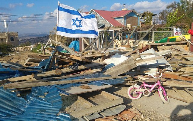 Un drapeau israélien flotte sur les ruines d'une maison en bois dans l'avant-poste de Netiv Ha'avot après sa démolition par les forces de sécurité israéliennes le 29 novembre 2017. (Crédit : autorisation Campagne pour sauver Netiv Haavot) Un drapeau israélien flotte sur les ruines d'une maison en bois dans l'avant-poste de Netiv Ha'avot après sa démolition par les forces de sécurité israéliennes le 29 novembre 2017. (Crédit : autorisation Campagne pour sauver Netiv Haavot)
