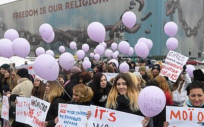 Des militantes brandissent des pancartes et des ballons pendant une marche féministe dans la ville ukrainienne de Kiev pour marquer la Journée internationale des droits des femmes, le 8 mars 2018 (Crédit : AFP/Sergei SUPINSKY)