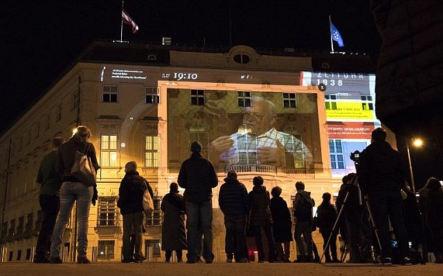 Les gens regardent 'Zeituhr 1938', une projection sur la façade de la chancellerie autrichienne qui retrace les moments obscurs menant à la prise par les nazis d'Adolf Hitler en 1938, un jour avant le 80ème anniversaire de l'annexion de l'Autriche ("Anschluss"), le 11 mars 2018 à Vienne en Autriche, le 11 mars 2018 (Crédit : / AFP PHOTO / JOE KLAMAR) Les gens regardent 'Zeituhr 1938', une projection sur la façade de la chancellerie autrichienne qui retrace les moments obscurs menant à la prise par les nazis d'Adolf Hitler en 1938, un jour avant le 80ème anniversaire de l'annexion de l'Autriche ("Anschluss"), le 11 mars 2018 à Vienne en Autriche, le 11 mars 2018 (Crédit : / AFP PHOTO / JOE KLAMAR)