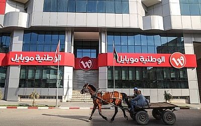 Des Palestiniens montent une charrette tirée par un cheval devant la porte fermée du siège social de la société Wataniya Mobile dans la ville de Gaza le 17 mars 2018. (AFP PHOTO / MAHMUD HAMS)