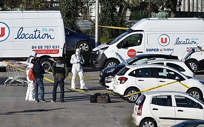 Des médecins légistes français arrivent à Trebes, dans le sud de la France, le 23 mars 2018, pour inspecter un véhicule (C, capot relevé) soupçonné d'appartenir au preneur d'otages et stationné devant le supermarché Super U de la ville de Trèbes, dans le sud de la France. (AFP PHOTO / PASCAL PAVANI)