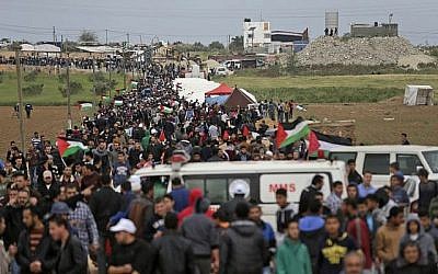 Les Palestiniens franchissent une ville de tente dressée le long de la frontière avec Israël, à l'est de Gaza City, pour commémorer la Journée de la terre (Crédit : AFP/ MAHMUD HAMS)