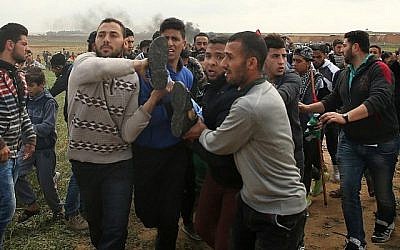 Une photo prise le 30 mars 2018 montre un adolescent palestinien transporté sur une civière après avoir été blessé lors d'une manifestation près de la frontière avec Israël à l'est de Jabalia dans la bande de Gaza pour commémorer la Journée de la Terre (Crédit : AFP / Mohammed ABED)