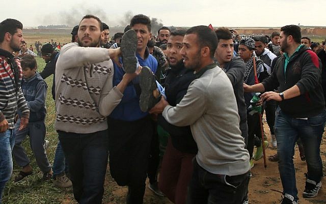 Une photo prise le 30 mars 2018 montre un jeune Palestinien transporté sur un brancard après avoir été blessé lors d'une manifestation à proximité de la frontière à l'est de Jabalia, lors de la journée palestinienne de commémoration de la Terre.  (Crédit : AFP/ Mohammed ABED)