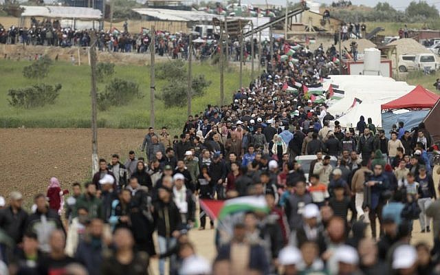 Les Palestiniens franchissent une ville de tentes dressées le long de la frontière avec Israël, à l'est de Gaza City, pour commémorer la Journée de la terre (Crédit : AFP/ MAHMUD HAMS)