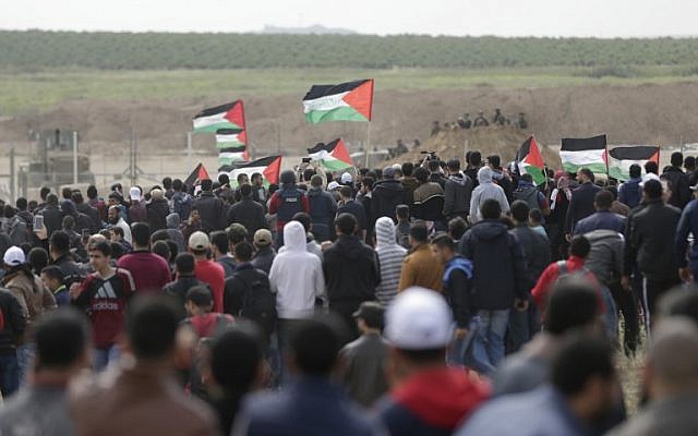 Les Palestiniens défilent devant une tente érigée le long de la frontière avec Israël à l'est de la ville de Gaza dans la bande de Gaza pour commémorer la Journée de la Terre, le 30 mars 2018 (Crédit : AFP PHOTO / MAHMUD HAMS)