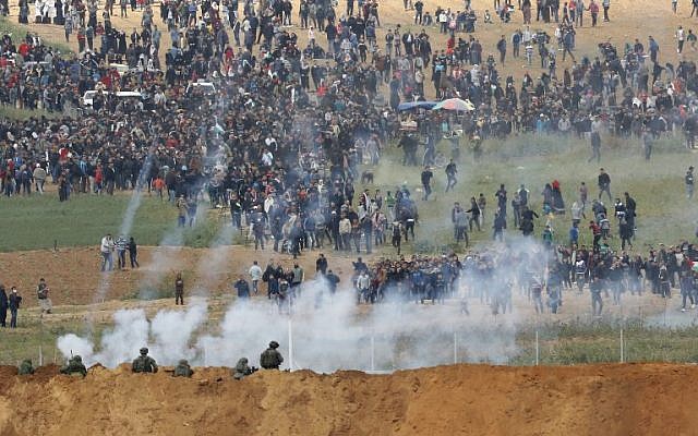 Une photo prise le 30 mars 2018 depuis le kibboutz de Nahal Oz de l'autre côté de la bande de Gaza montre des Palestiniens participant à une manifestation pour commémorer la Journée de la Terre (Crédit : AFP / Jack GUEZ) Une photo prise le 30 mars 2018 depuis le kibboutz de Nahal Oz de l'autre côté de la bande de Gaza montre des Palestiniens participant à une manifestation pour commémorer la Journée de la Terre (Crédit : AFP / Jack GUEZ)