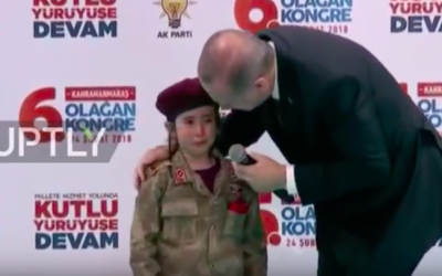 Le président turc Recep Tayyip Erdogan aux côtés d'une fillette portant un uniforme des forces spéciales turques en larmes sur une estrade lors d'un meeting de l'AKP, le 28 février 2018 (Crédit : capture d'écran YouTube)