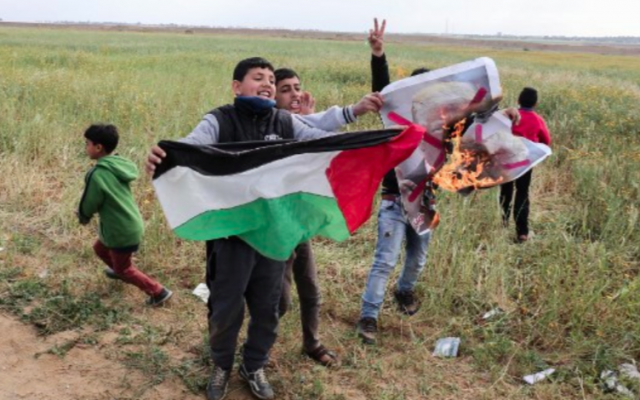 Des enfants de la bande de Gaza agitent un drapeau palestinien et brûle un drapeau à l'effigie de Donald Trump, le 30 mars 2018 (Crédit : Said Khatib/AFP) Des enfants de la bande de Gaza agitent un drapeau palestinien et brûle un drapeau à l'effigie de Donald Trump, le 30 mars 2018 (Crédit : Said Khatib/AFP)