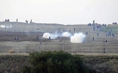 Des manifestants palestiniens près de la clôture de la frontière israélienne avec la bande de Gaza alors que les soldats israéliens utilisent des gaz lacrymogènes, 3 janvier 2014. (David Buimovitch/Flash90)