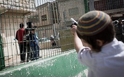 Illustration : Des habitants d'implantation israéliens taquinent des Palestiniens alors que la parade annuelle marquant la fête juive de Pourim passe par la ville divisée de Hébron, en Cisjordanie, le 1er mars 2018 (Crédit :   Hadas Parush/Flash90)