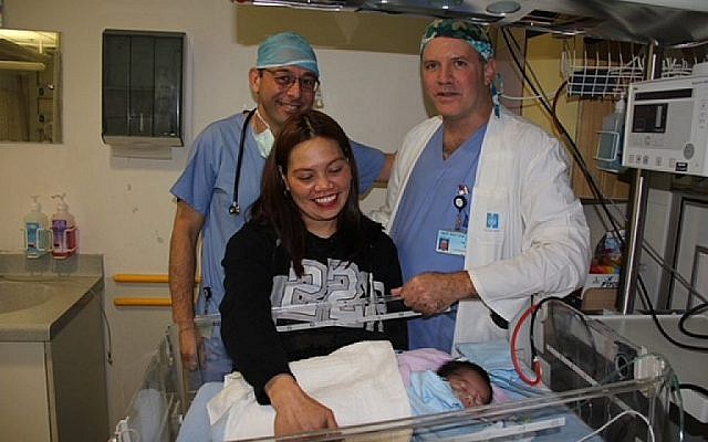 Le Dr Julius Golender, à gauche, et le Dr Gavri Sagi posent pour une photo avec la mère philippine Nina et son bébé Francis Joseph, qui est né avec une malformation cardiaque rare et dont la vie a été sauvée à l'hôpital Hadassah de Jérusalem en février 2018. (Hôpital Hadassah)