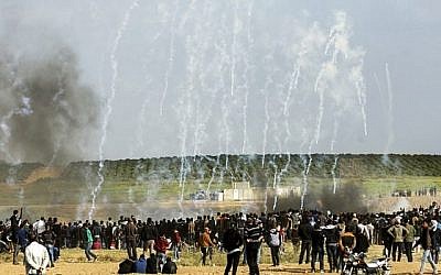 Des manifestants palestiniens face au gaz lacrymogène tiré par les forces de sécurité israéliennes lors d'affrontements à la suite d'une manifestation commémorant le Jour de la Terre, près de la frontière avec Israël, à l'est de Gaza le 30 mars 2018. (Mahmud Hams / AFP)