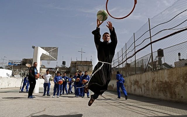 Un frère franciscain joue au basket-ball avec les enfants de l'école Terra Sancta lors d'une séance de sport dans la Vieille Ville de Jérusalem, le 1er mars 2018. (AFP PHOTO / Thomas COEX) Un frère franciscain joue au basket-ball avec les enfants de l'école Terra Sancta lors d'une séance de sport dans la Vieille Ville de Jérusalem, le 1er mars 2018. (AFP PHOTO / Thomas COEX)