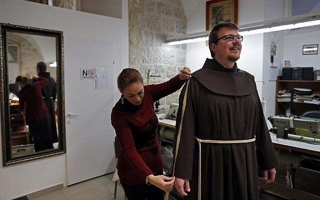 Une femme tailleur chrétienne palestinienne prend les mesures d'un frère franciscain pour une nouvelle tenue de pénitent dans un atelier de couture à l'intérieur du couvent Saint Sauveur, siège franciscain dans la Vieille Ville de Jérusalem, le 2 février 2018. (AFP PHOTO / Thomas COEX) Une femme tailleur chrétienne palestinienne prend les mesures d'un frère franciscain pour une nouvelle tenue de pénitent dans un atelier de couture à l'intérieur du couvent Saint Sauveur, siège franciscain dans la Vieille Ville de Jérusalem, le 2 février 2018. (AFP PHOTO / Thomas COEX)