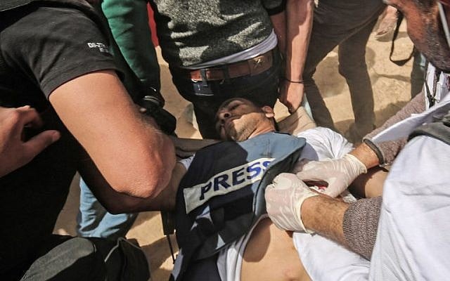 Des manifestants aident le journaliste palestinien blessé Yasser Murtaja lors d'affrontements avec les forces de sécurité israéliennes, à la suite d'une manifestation près de la frontière avec Israël, à l'est de Khan Younès, dans le sud de la bande de Gaza, le 6 avril 2018. Il a succombé à ses blessures. (AFP PHOTO / DIT KHATIB) Des manifestants aident le journaliste palestinien blessé Yasser Murtaja lors d'affrontements avec les forces de sécurité israéliennes, à la suite d'une manifestation près de la frontière avec Israël, à l'est de Khan Younès, dans le sud de la bande de Gaza, le 6 avril 2018. Il a succombé à ses blessures. (AFP PHOTO / DIT KHATIB)