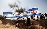 Des manifestants palestiniens brûlent un drapeau israélien lors d'affrontements avec les forces de sécurité israéliennes à la frontière entre Gaza et Israël, à l'est de Khan Younès, dans le sud de la bande de Gaza, le 6 avril 2018. (AFP PHOTO / DIT KHATIB)
