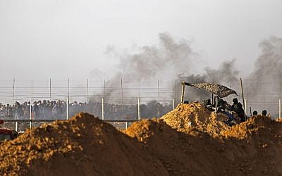 Les forces israéliennes déployées aux abords du  Kibbutz Kerem Shalom sur la frontière israélienne au sud de la bande de Gaza alors que la fumée de pneus brûlés par les Palestiniens se dégage, le 6 avril 2018 (Crédit : AFP PHOTO / MENAHEM KAHANA