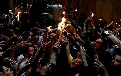 Les fidèles chrétiens orthodoxes tiennent des bougies allumées au "feu sacré" lors d'un rassemblement à l'église du Saint-Sépulcre de la Vieille Ville de Jérusalem lors de la Pâque orthodoxe, le 7 avril 2018 
 (Crédit : AFP PHOTO / GALI TIBBON)
