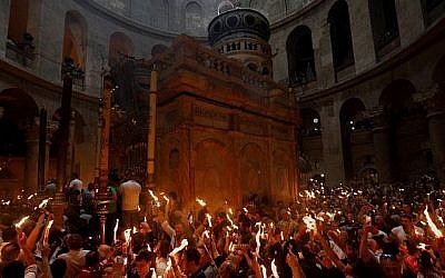 Les fidèles chrétiens orthodoxes tiennent des bougies allumées au "feu sacré" lors d'un rassemblement à l'église du Saint-Sépulcre de la Vieille Ville de Jérusalem lors de la Pâque orthodoxe, le 7 avril 2018 
 (Crédit : AFP PHOTO / GALI TIBBON)