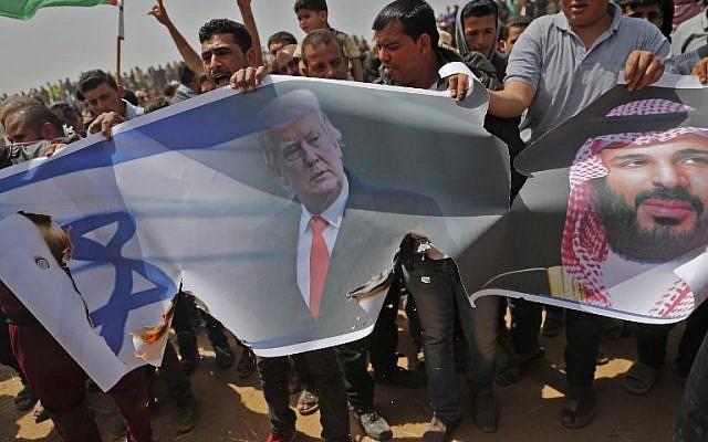 Les Palestiniens s'apprêtent à incendier un drapeau israélien et des portraits du président américain Donald Trump et du prince héritier saoudien Mohammed ben Salmane lors d'une manifestation contre la barrière frontalière avec Israël, à l'est de Khan Younès, au sud de Gaza, le 13 avril 2018. (Crédit : AFP PHOTO / Thomas COEX)