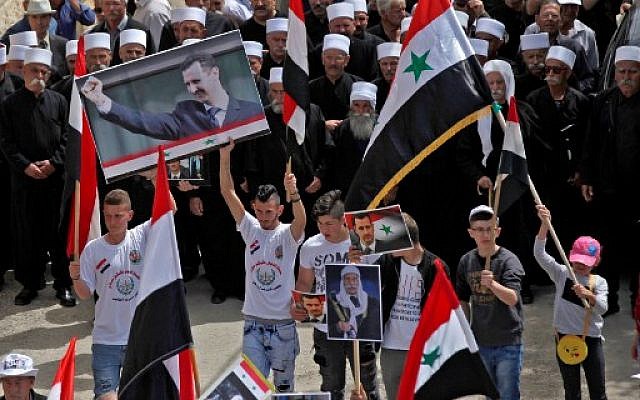 Les habitants druzes du village d'Ein Qiniye dans les hauteurs du Golan brandissent des drapeaux syriens et des images du président syrien lors d'un rassemblement marquant le Jour de l'Indépendance de la Syrie le 17 avril 2018. (Crédit : AFP / JALAA MAREY) Les habitants druzes du village d'Ein Qiniye dans les hauteurs du Golan brandissent des drapeaux syriens et des images du président syrien lors d'un rassemblement marquant le Jour de l'Indépendance de la Syrie le 17 avril 2018. (Crédit : AFP / JALAA MAREY)