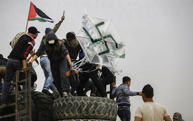 Les Palestiniens tiennent un cerf-volant orné d'une croix gammée portant une bombe près de la frontière avec Israël à l'est de la ville de Gaza, le 20 avril 2018. (AFP Photo / Mohammed Abed)