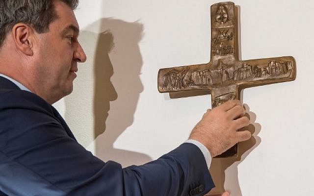 Cette photo prise le 24 avril 2018 à Munich montre Markus Soeder, Premier ministre bavarois, alors qu'il accroche une croix dans l'entrée de la Chancellerie de l'État de la Bavière (Crédit : AFP PHOTO / dpa / Peter Kneffel / Allemagne OUT) Cette photo prise le 24 avril 2018 à Munich montre Markus Soeder, Premier ministre bavarois, alors qu'il accroche une croix dans l'entrée de la Chancellerie de l'État de la Bavière (Crédit : AFP PHOTO / dpa / Peter Kneffel / Allemagne OUT)